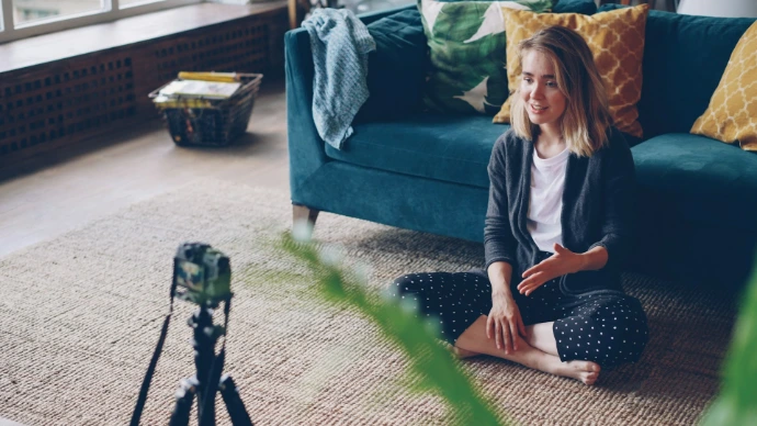 Woman sitting on floor recording video with camera.